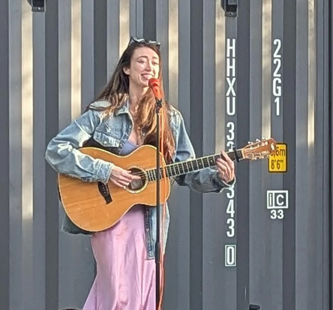 Sierra “Sisi” Moses mid-song with her acoustic guitar during an outdoor set